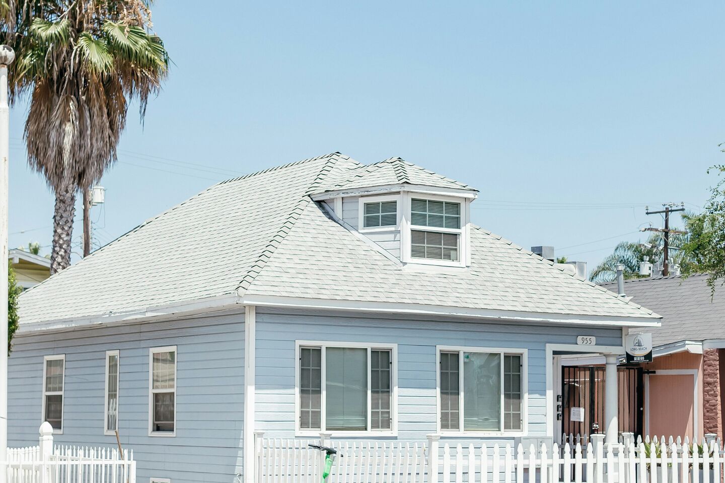 Light blue two-story house with a dormer and a palm tree