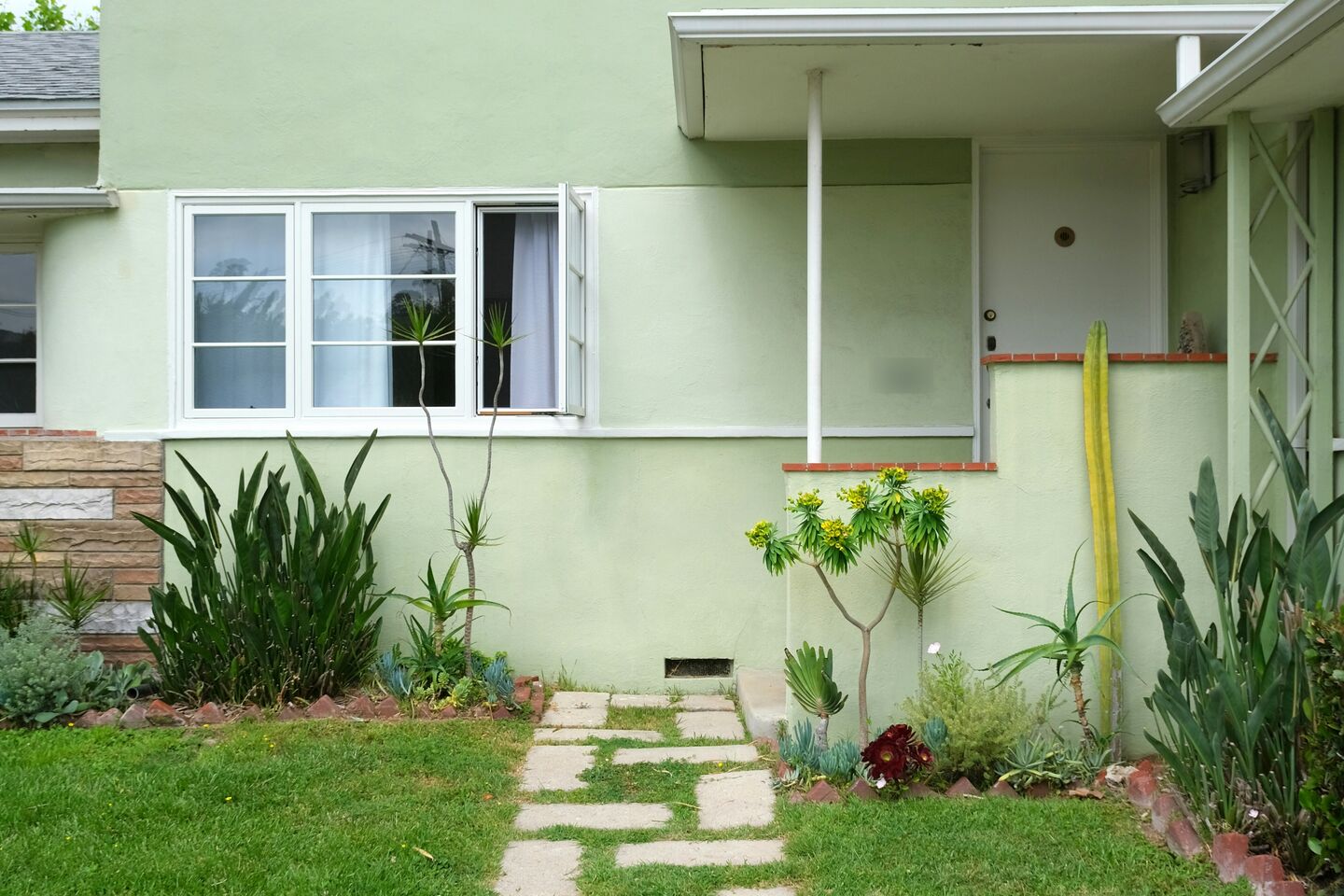 Pale green stucco house with a stepping-stone path across the lawn